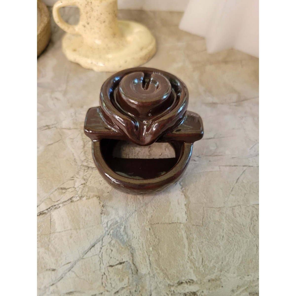 Brown ceramic back flow incense burner on a marble surface