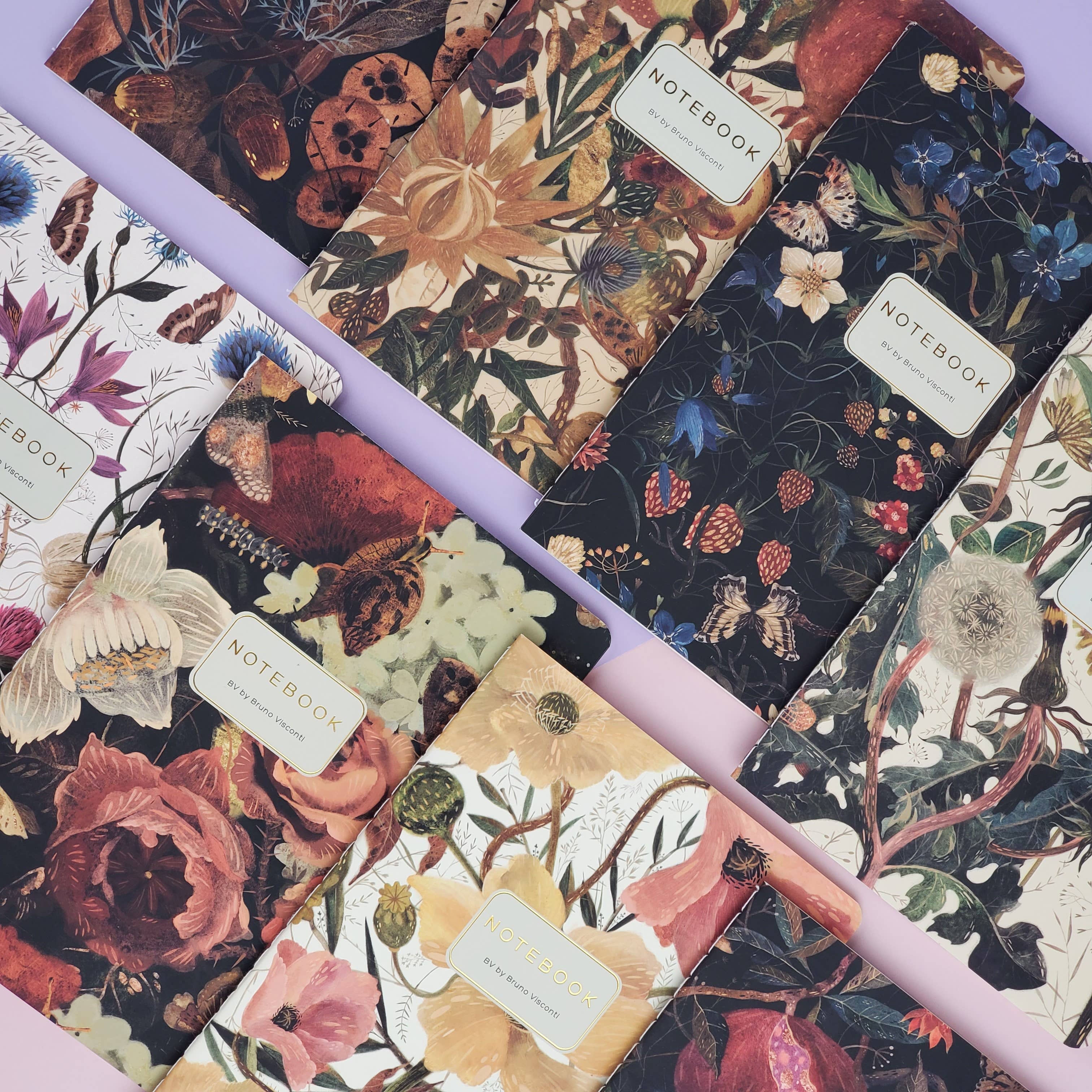 Floral-patterned notebooks with visible brand labels on a matching floral background.