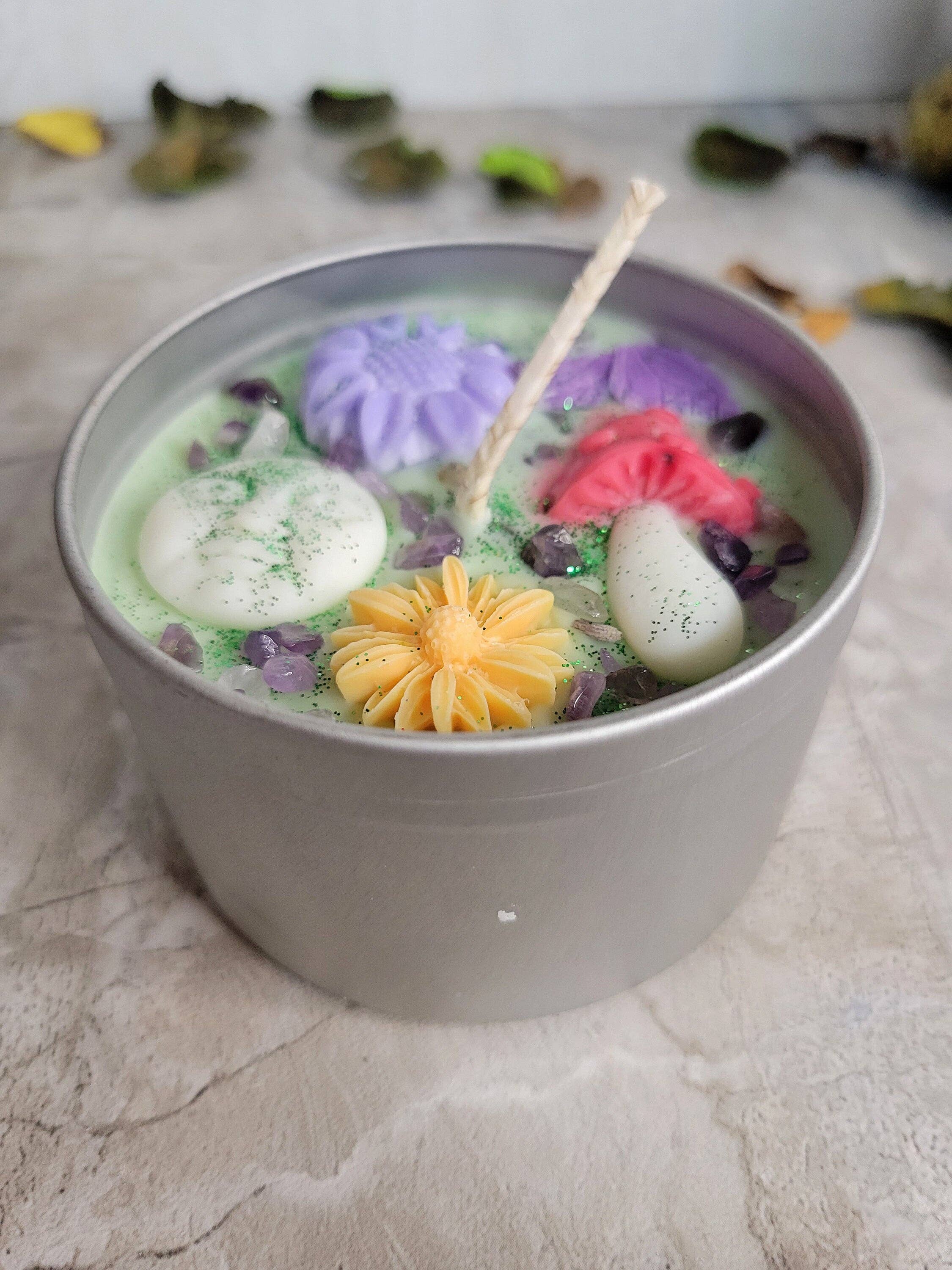 Candle in a gray container with colorful wax flowers on a textured surface