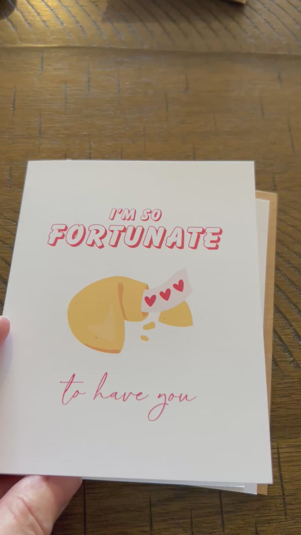 Short Video oF "I's SO Fortunate to have you" Greeting card with a fortune cookie and hearts as the fortune coming out of the cookie.  Shows white blank inside and back of card.  On a wood surface.